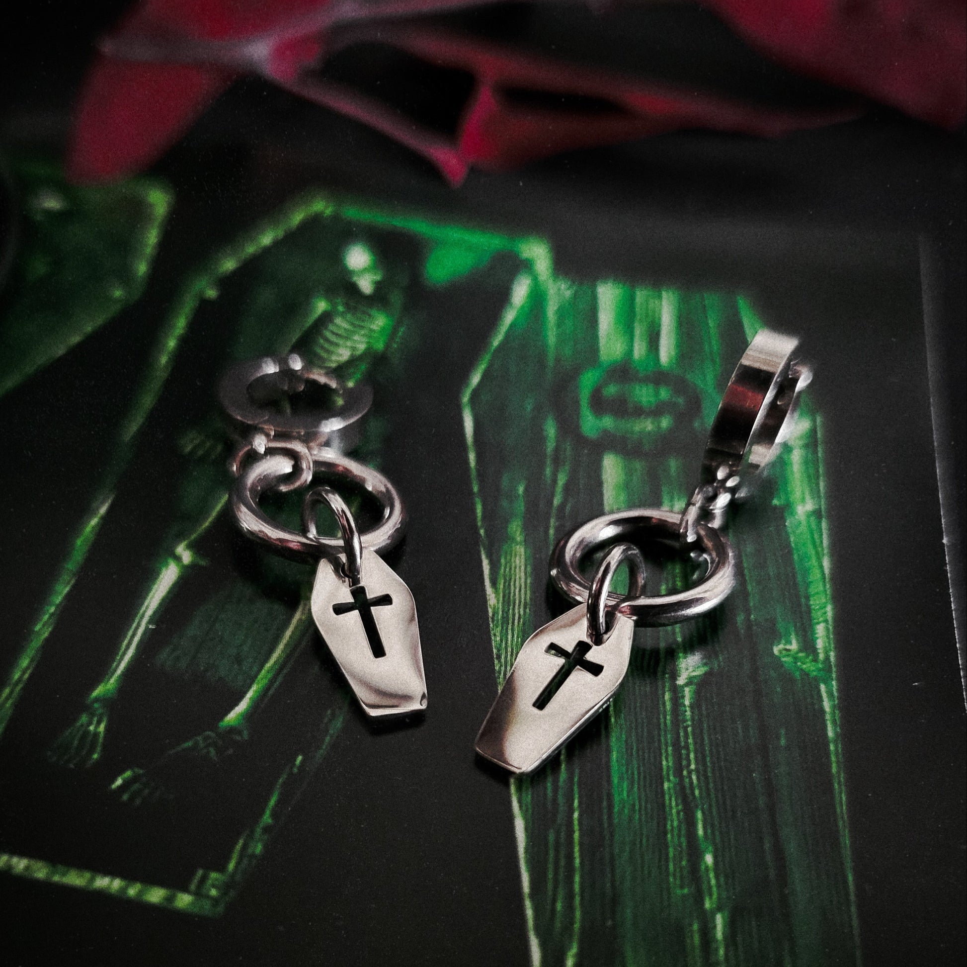 Silver coffin charms with cross designs on a dark surface