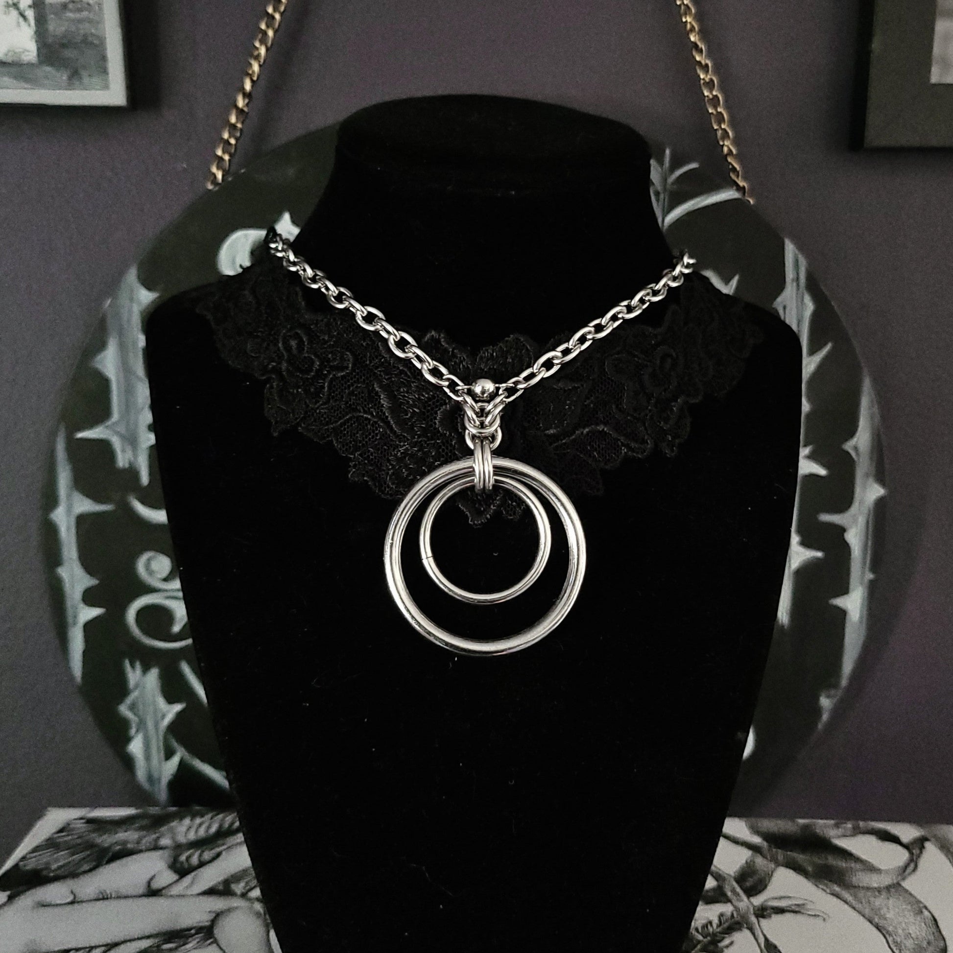 Necklace with circular pendant on a black velvet stand against a dark background