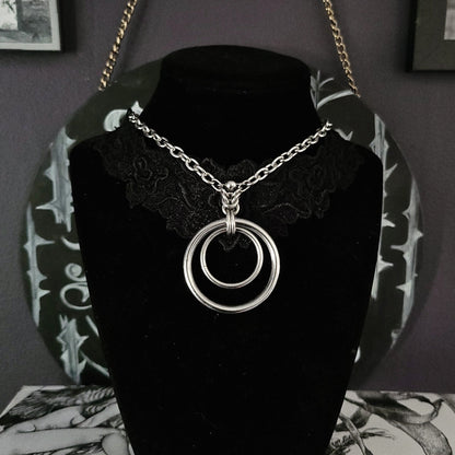 Necklace with circular pendant on a black velvet stand against a dark background