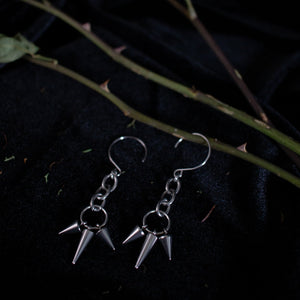 Pair of silver earrings dangling with short and long spikes hanging from chain links.