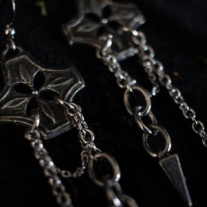 Pair of silver earrings with chained spikes dangling from floral checkered pendant.