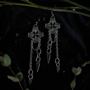 Pair of silver earrings with chained spikes dangling from floral checkered pendant.